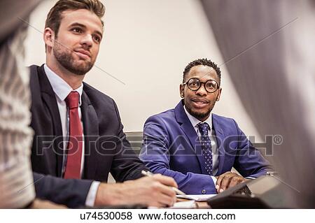 Stock Photo - Businessmen at boardroom table meeting. Fotosearch