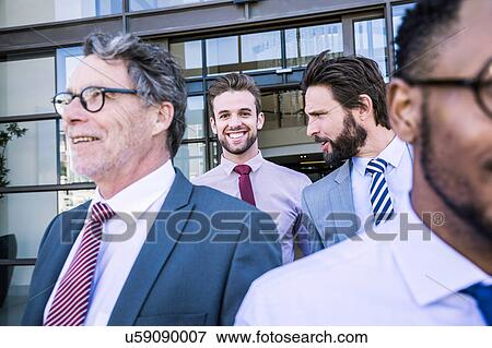 Businessmen talking whilst leaving office building View Large Photo Image Stock Photo - Businessmen talking whilst leaving office building. Fotosearch