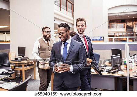 Businessmen walking through office with takeaway coffee View Large Photo Image Stock Photo - Businessmen walking through office with takeaway coffee. Fotosearch