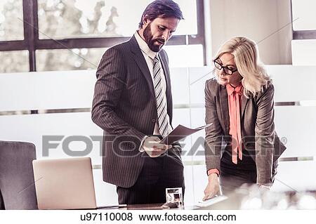 Stock Photo - Businesswoman and businessman reading paperwork in office. Fotosearch