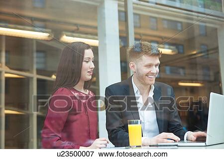 Stock Photo - Businesswoman and businessman working with laptop in cafe. Fotosearch