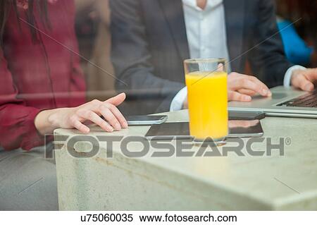 Stock Photography - Businesswoman and businessman working with laptop in cafe. Fotosearch
