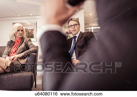 Stock Photograph - Businesswoman and businessmen at armchair meeting. Fotosearch