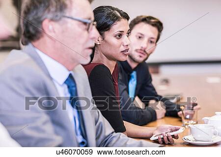 Stock Photo - Businesswoman and businessmen listening in board meeting. Fotosearch
