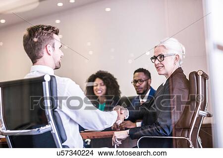 Businesswoman and man shaking hands in board team meeting View Large Photo Image Picture - Businesswoman and man shaking hands in board team meeting. Fotosearch