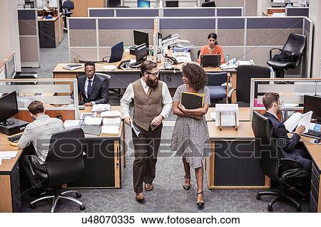 Stock Photography - Businesswoman and man walking and talking in office. Fotosearch