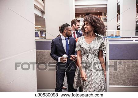 Businesswoman and men walking and talking in office View Large Photo Image Stock Photo - Businesswoman and men walking and talking in office. Fotosearch