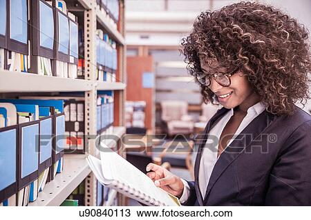 Businesswoman reading file from office shelves View Large Photo Image Stock Image - Businesswoman reading file from office shelves. Fotosearch