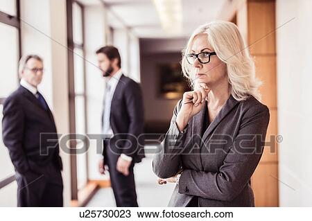 Businesswoman with hand on chin in office corridor View Large Photo Image Stock Image - Businesswoman with hand on chin in office corridor. Fotosearch