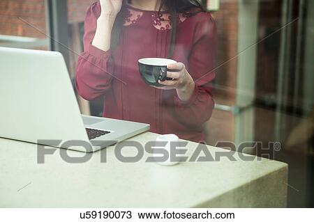 Stock Image - Businesswoman working with laptop in cafe. Fotosearch