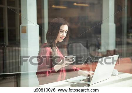 Stock Photograph - Businesswoman working with laptop in cafe. Fotosearch
