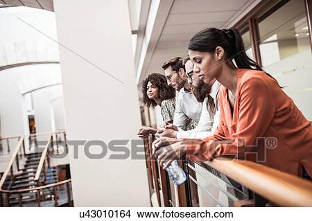 Businesswomen and men looking out from office balcony View Large Photo Image Picture - Businesswomen and men looking out from office balcony. Fotosearch