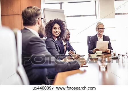 Stock Photo - Businesswomen and men talking at conference table meeting. Fotosearch