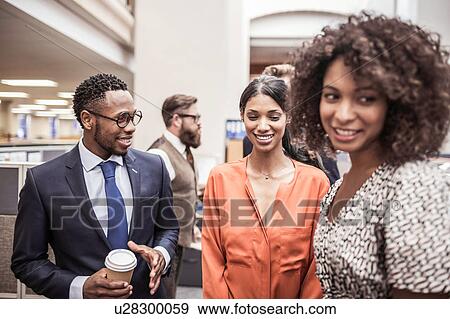 Stock Photo - Businesswomen and men talking in office. Fotosearch