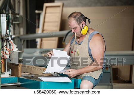 Stock Image - Carpenter reading order instructions. Fotosearch