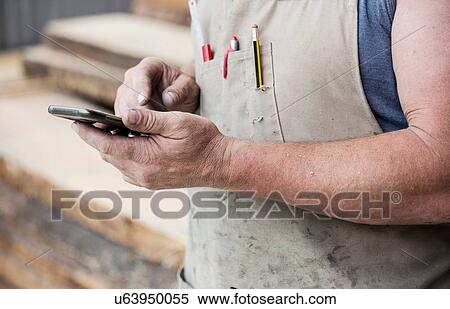 Stock Photography - Carpenter using cellphone. Fotosearch