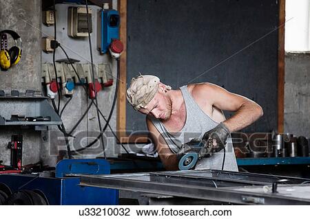 Stock Image - Carpenter working in workshop. Fotosearch