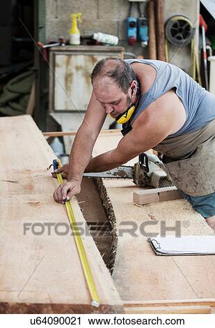 Stock Image - Carpenter working in workshop. Fotosearch