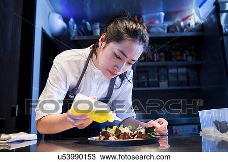 Stock Image - Chef dressing prepared meal. Fotosearch