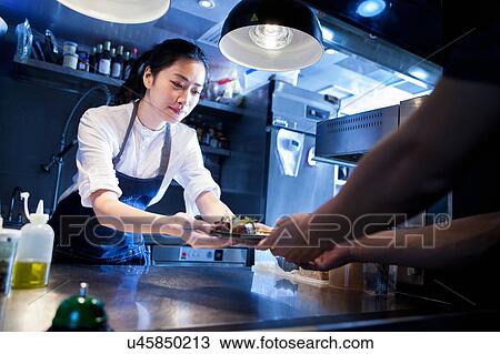 Chef handing prepared meal to waiter View Large Photo Image Stock Image - Chef handing prepared meal to waiter. Fotosearch