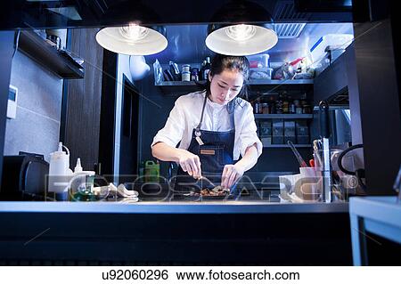 Stock Photograph - Chef in commercial kitchen preparing food. Fotosearch