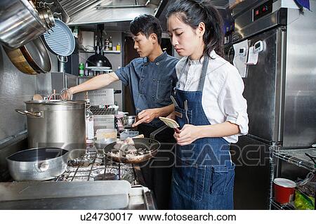 Chefs cooking in commercial kitchen View Large Photo Image Stock Photo - Chefs cooking in commercial kitchen. Fotosearch
