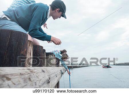 Stock Image - Children fishing on pier, Southwold, Suffolk, UK. Fotosearch