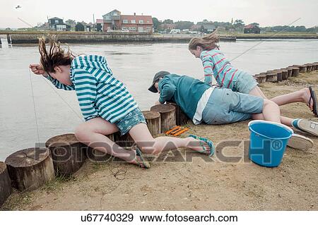 Stock Photo - Children looking over side of pier into water, Southwold, Suffolk, UK. Fotosearch