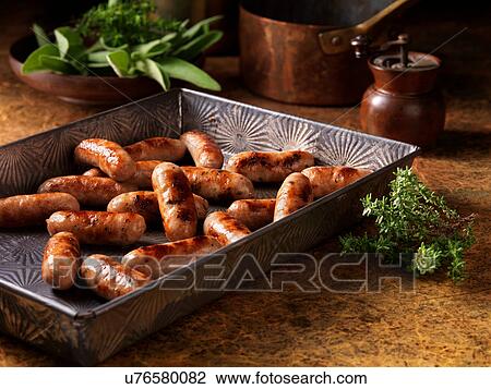Stock Image - Christmas, celebration food, classic cocktail sausage selection, in baking tray, fresh thyme and sage. Fotosearch