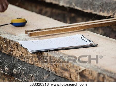 Stock Photograph - Clipboard, measuring tape on wooden plank. Fotosearch