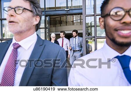 Stock Photo - Close up of businessmen leaving office building. Fotosearch