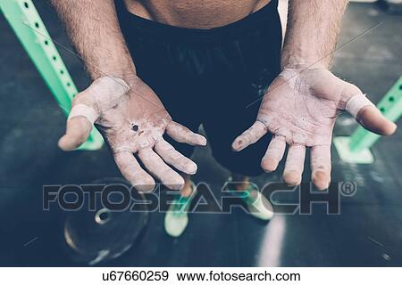 Stock Photo - Close up of male cross trainers chalked hands in gym. Fotosearch
