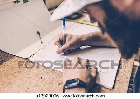 Stock Photograph - Close up of man writing on calendar at gym reception desk. Fotosearch