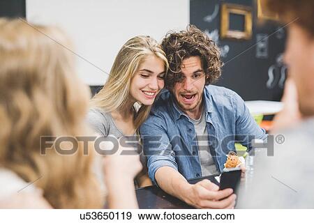 Stock Photo - Co-workers having morning break at table. Fotosearch