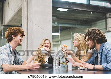 Stock Photo - Co-workers having morning break at table. Fotosearch