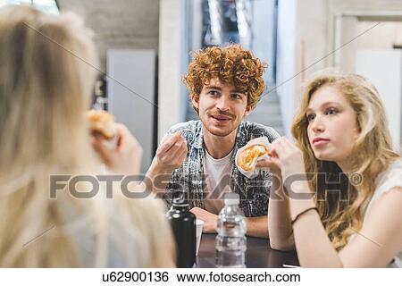 Co-workers having morning break at table View Large Photo Image Stock Photograph - Co-workers having morning break at table. Fotosearch
