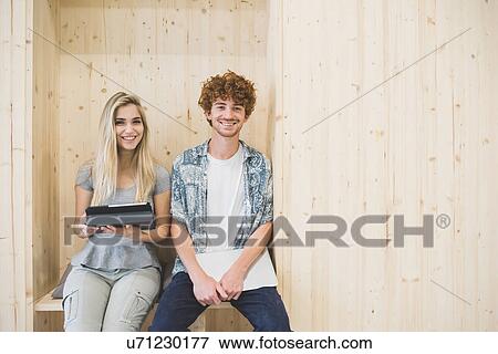 Co-workers using digital tablet in wooden panelled seating area View Large Photo Image Stock Photo - Co-workers using digital tablet in wooden panelled seating area. Fotosearch