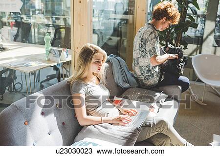 Stock Image - Co-workers working in open plan office. Fotosearch