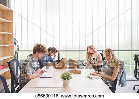 Co-workers working in open plan office View Large Photo Image Stock Photograph - Co-workers working in open plan office. Fotosearch