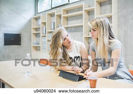 Co-workers working on digital tablet in office View Large Photo Image Picture - Co-workers working on digital tablet in office. Fotosearch