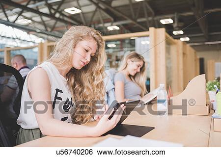 Stock Photograph - Co-workers working on digital tablet in open plan office. Fotosearch