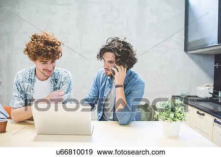 Stock Photo - Co-workers working on laptop in office. Fotosearch