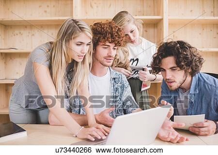 Stock Photograph - Co-workers working on laptop in office. Fotosearch