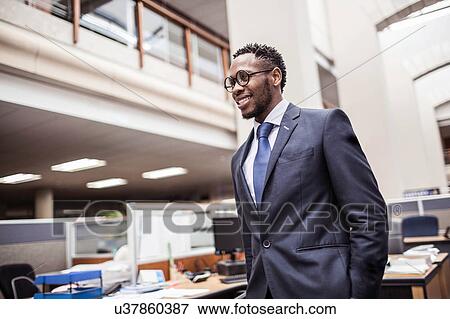 Confident young businessman in office View Large Photo Image Stock Photo - Confident young businessman in office. Fotosearch