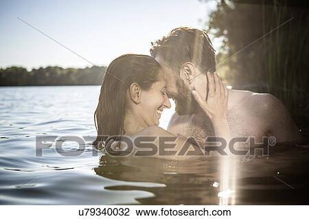 Stock Image - Couple face to face hugging, smiling in water, Berlin, Germany. Fotosearch