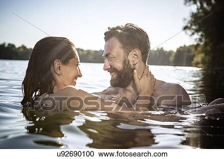 Stock Image - Couple face to face hugging, smiling in water, Berlin, Germany. Fotosearch