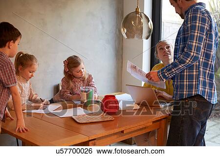 Couple having discussion at dining table whilst son and daughters colouring View Large Photo Image Stock Photograph - Couple having discussion at dining table whilst son and daughters colouring. Fotosearch