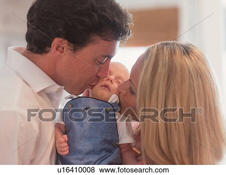 Stock Photo - Couple kissing baby son (0-1 months). Fotosearch
