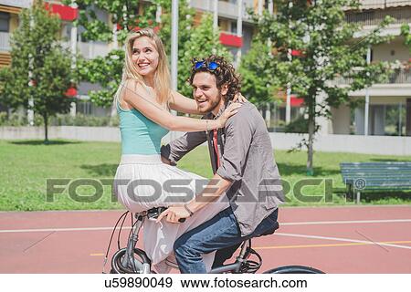 Couple on bicycle in park View Large Photo Image Stock Photo - Couple on bicycle in park. Fotosearch