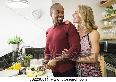 Stock Image - Couple preparing dinner in kitchen. Fotosearch